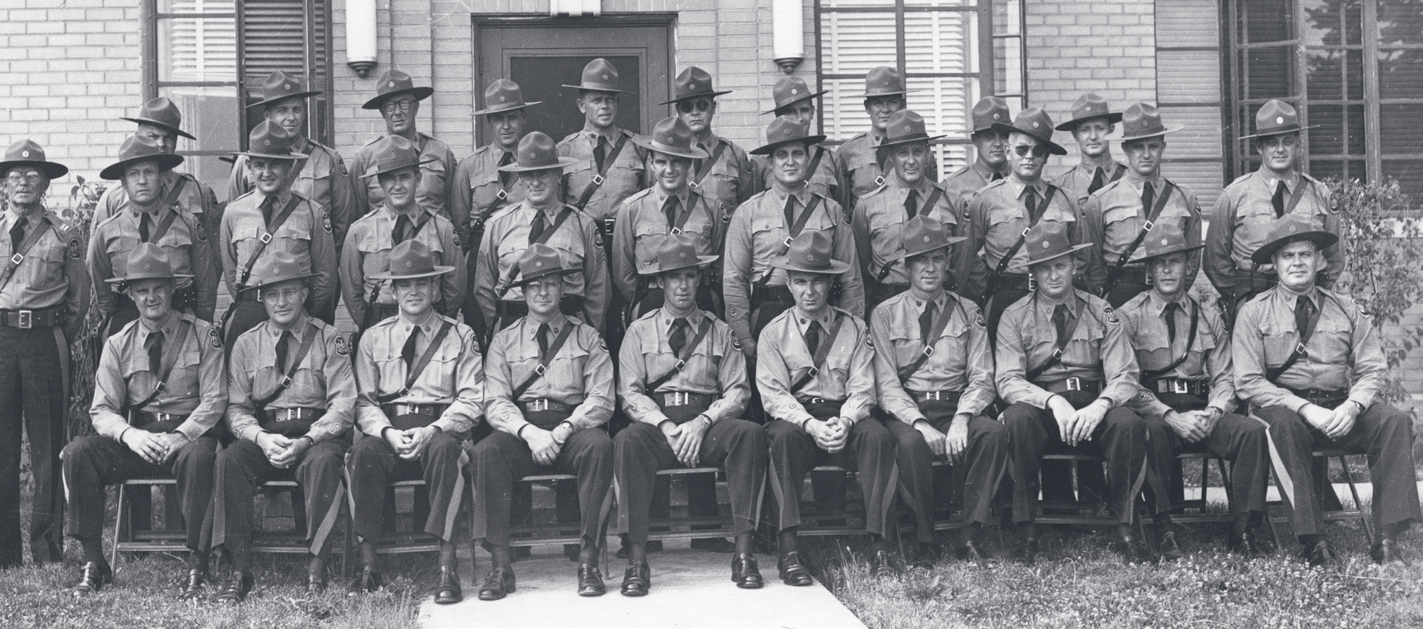 Black-and-white group portrait of approximately thirty MSHP officers in uniform and campaign hats, arranged in three rows outside a building.