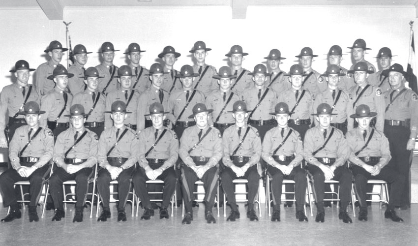 A group of approximately twenty uniformed MSHP officers in campaign hats pose in formation with rifles held at their sides.