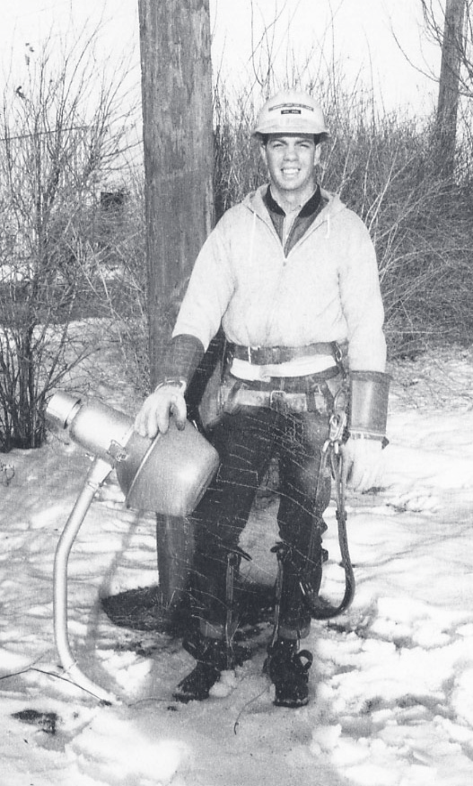 Cpl. Bruns stands outdoors in winter holding fire hose equipment, wearing a helmet and uniform.
