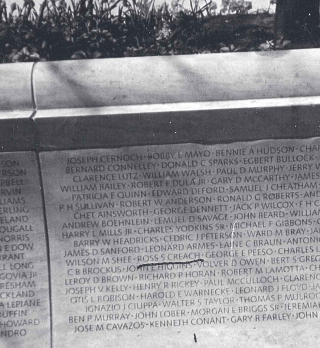Close-up of an engraved memorial wall listing fallen officers' names, including Ross S. Creach, amid rows of other names.