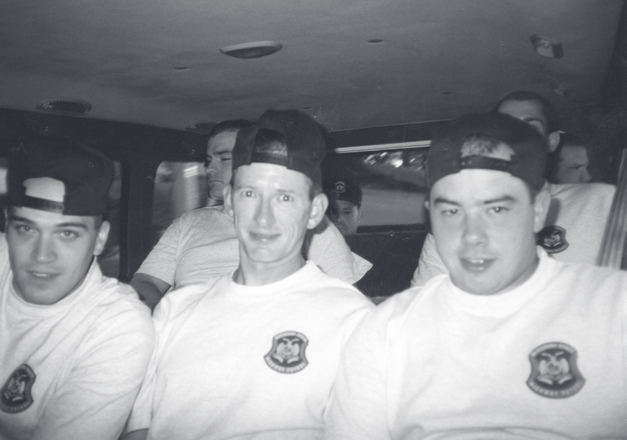 Cpl. Engelhard sits between two other officers in matching white t-shirts with patrol patches and dark ball caps.
