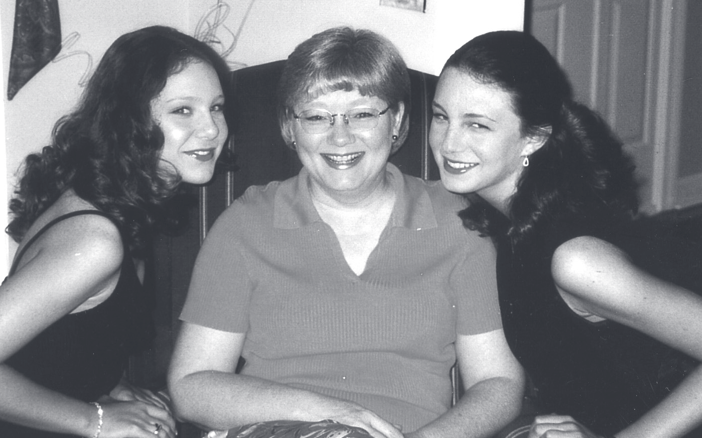 Three family members smile closely together in an indoor candid portrait.