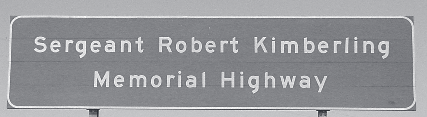 A green highway sign reads 'Sergeant Robert Kimberling Memorial Highway.'