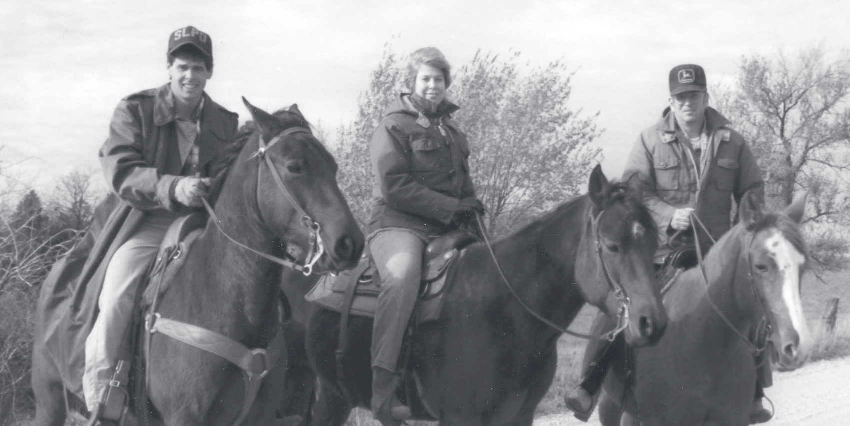 Tpr. Kolilis rides horseback on a trail alongside two other mounted officers among trees.