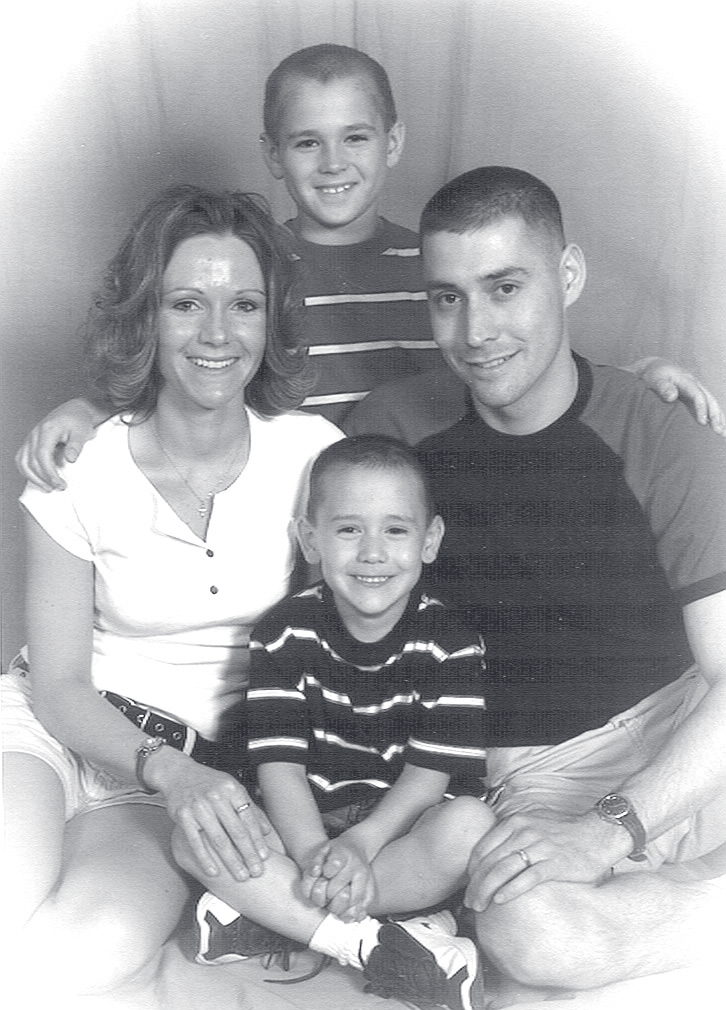 Tpr. Newton seated with a woman and two young boys in a family portrait.