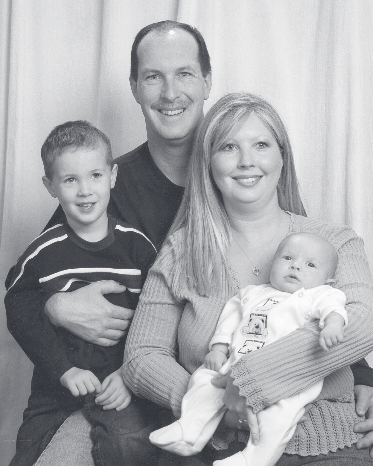 Black-and-white family portrait of Cpl. Sampietro with a woman holding an infant and a young boy beside them.