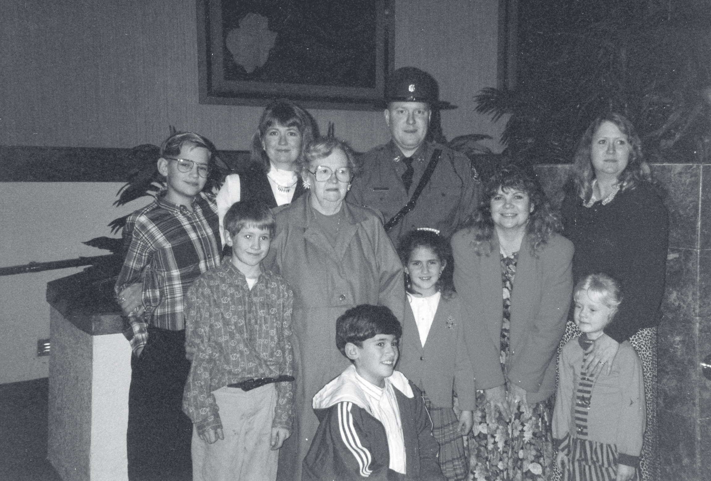 Sgt. Schuengel in uniform stands with a group of family members, including adults and children, in an indoor setting.