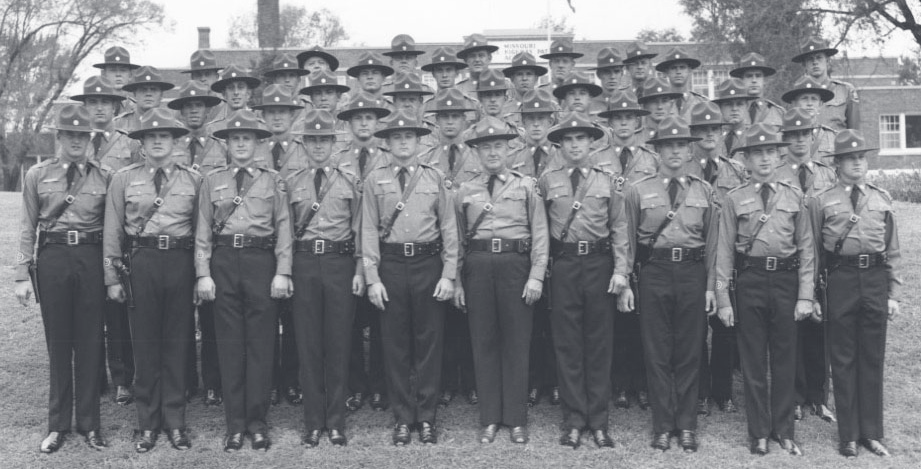 Black-and-white group photograph of uniformed MSHP officers posed in multiple rows outdoors in front of a building.