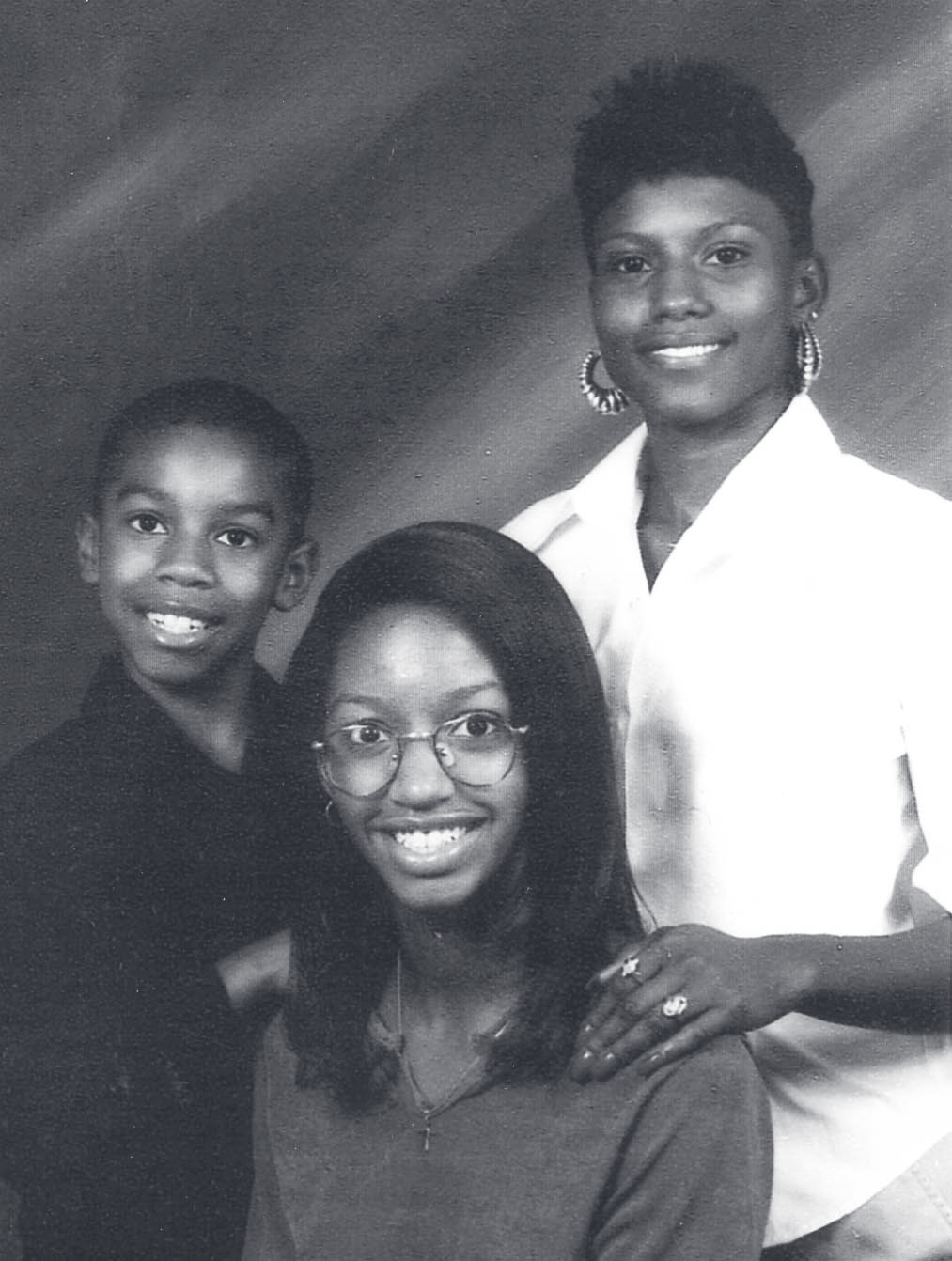 Studio portrait of a woman and two children posed together against a plain backdrop.
